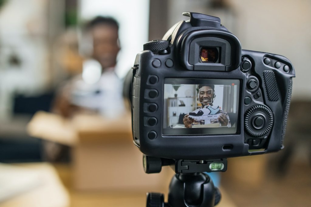 Afro american man unboxing sneakers and recording video